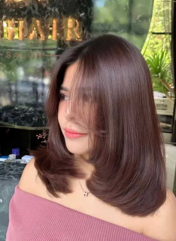 Sleek, straight dark brown shoulder-length hair with a precise center part