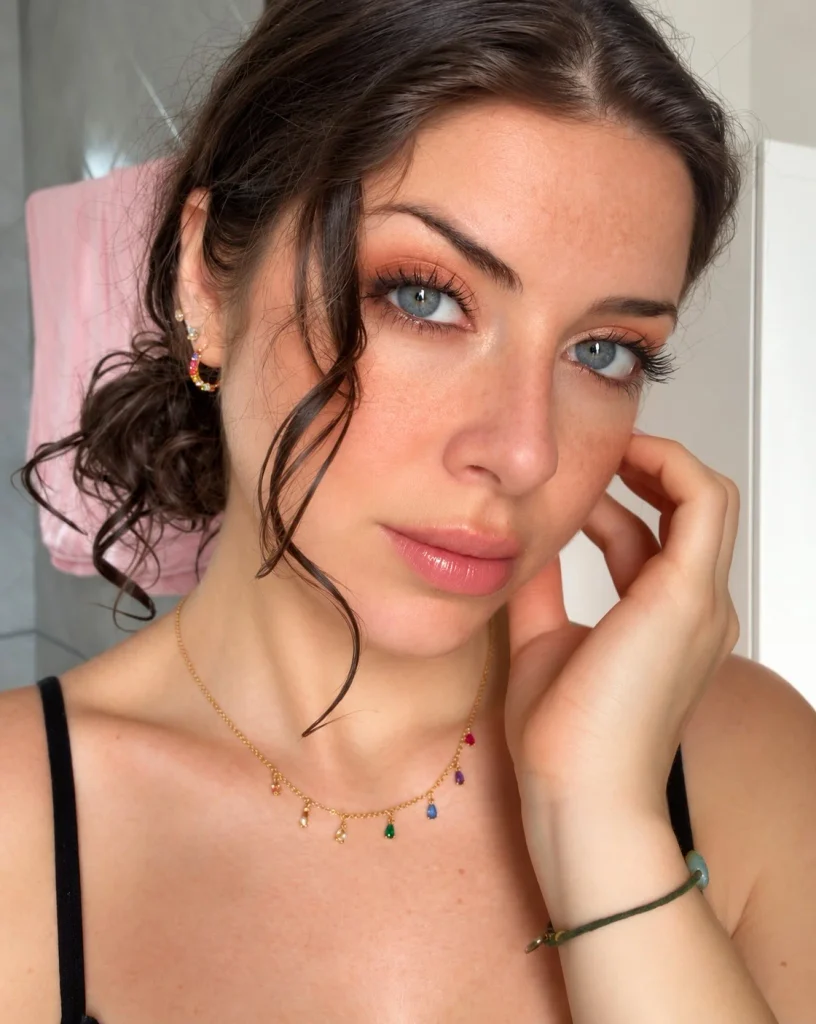 Blue eyes with soft peach eyeshadow on the lids, champagne shimmer in the inner corners, and subtle neutral definition.