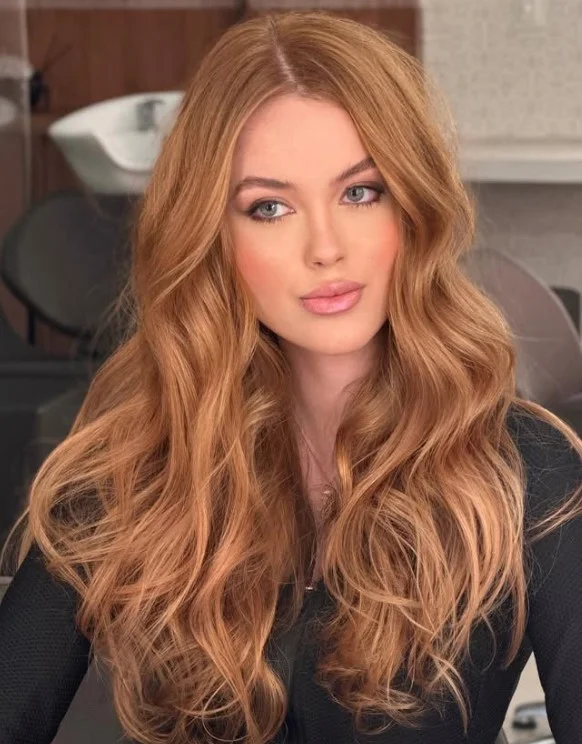 Woman with strawberry blonde hair blending soft golden blonde and subtle reddish tones for a delicate, natural-looking finish.