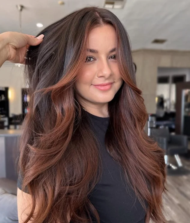 Warm auburn brown hair with visible copper-red tones through layered lengths.