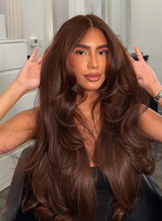 Woman with warm chestnut brown hair featuring subtle reddish brown tones and soft waves